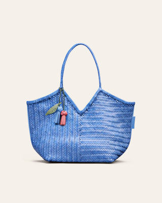 Cala Jade blue woven shoulder bag with a bag charm attached on a beige background
