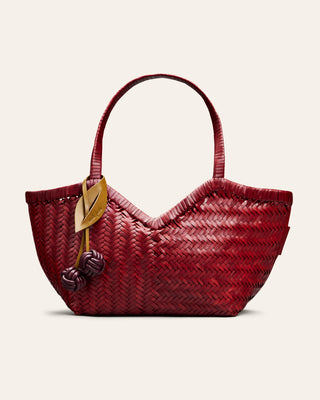 Cala Jade woven red handbag with a cherry shaped bag charm on a beige background