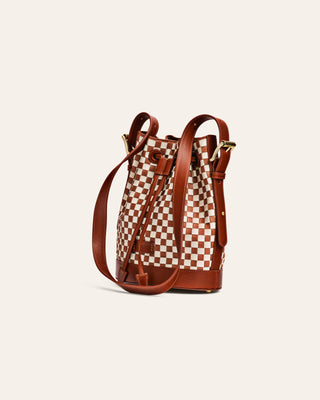 Checkered bucket bag with brown leather straps on a beige background