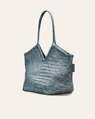 Blue woven leather handbag with a handle on a light beige background