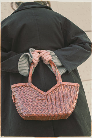 Cala Jade Person holding a woven handbag with a neutral background