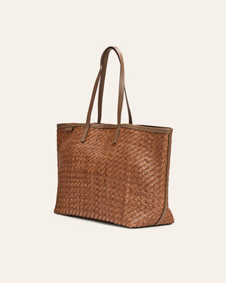 Brown woven tote bag with leather handles on a beige background