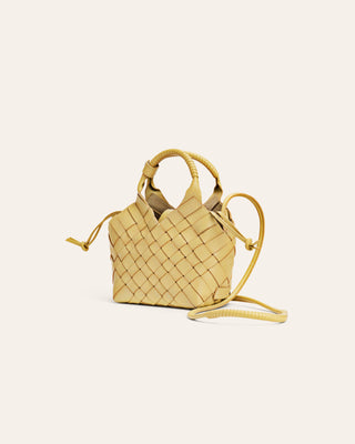 Small woven yellow handbag on a light beige background