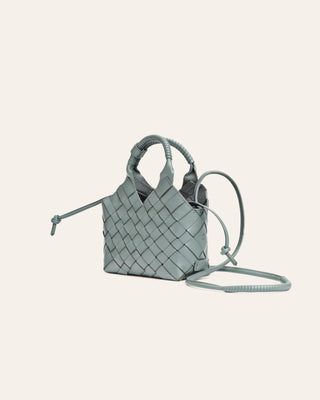 Light blue woven handbag with a strap on a light gray background