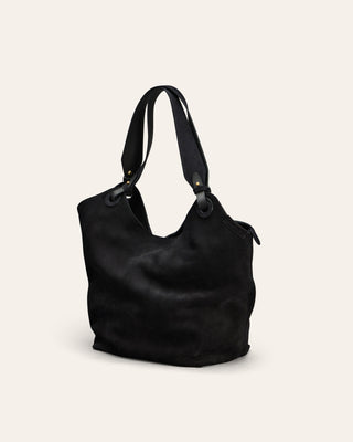 Black suede handbag on a light beige background