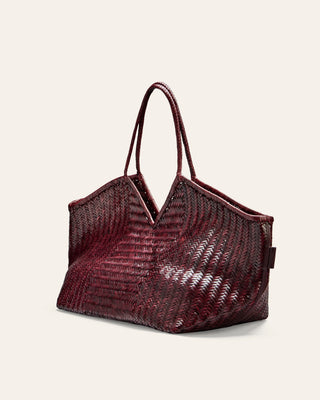 Burgundy woven handbag with a textured pattern on a light beige background