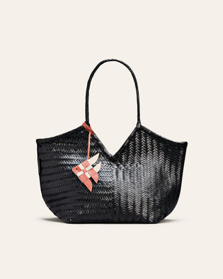 Black woven handbag with a pink fish charm on a light beige background