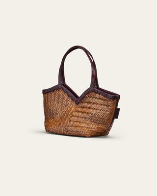 A beige and burgundy woven shoulder bag on a beige background seen from the side