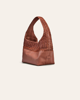 Coral leather handbag with perforated design on a beige background