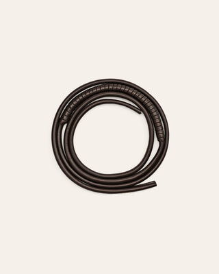 A brown leather shoulder strap on a beige background