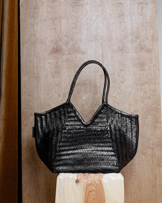 A black leather bag on a wooden pidestal